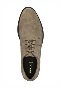 Zapato de ante beige con textura suave, punta redondeada, cordones de cinco ojales y suela de goma negra. Presenta la marca Geox en el interior.