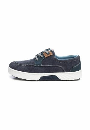 Zapato casual azul marino con parte superior de tela, acento en contraste en color tan y suela de goma blanca. Presenta cordones grises y detalle de costura.