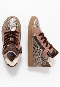 Kravate na vysoké špičce s leopardím vzorem v metalické zlaté a hnědé barvě, s hnědými koženými akcenty, šněrováním a bočním zipem, a útulnou podšívkou.