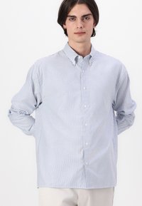 Camisa de botones a rayas azul y blanca, hecha de una tela ligera, con cuello, mangas largas y botones en la parte delantera.