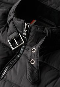 Schwarzer gesteppter Jackenkragen mit Reißverschluss und metallischen Akzenten. Mit Druckknopfverschluss und einem glatten, strukturierten Stoff ausgestattet. Leichtes Design.