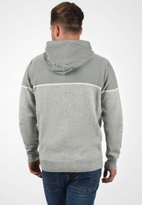 Haut à capuche gris avec tricot texturé, rayure horizontale gris clair et poignets côtelés. Doté d'une capuche avec cordon de serrage et d'une coupe décontractée.