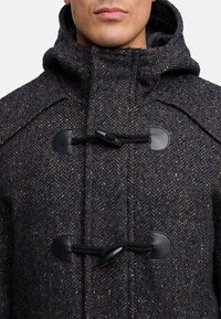 Dufflecoat aus Wollmischung in Dunkelblau mit Fischgrätmuster. Verfügt über schwarze Knebelverschlüsse und eine Kapuze. Weiches, strukturiertes Aussehen.