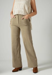 Beige corduroy wijde pijpen broek met voorzakken, met een zachte textuur en een hoge taille. Gecombineerd met een licht gebreid topje.