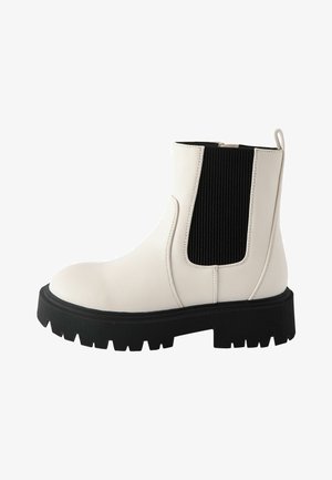 Bijele kožne gležnjače s crnim rebrastim elastičnim bočnim panelom i debelim crnim potplatom. Imaju petnu traku za lakše oblačenje.