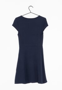 Navy sininen mekko, joka on valmistettu pehmeästä kankaasta. Mekossa on lyhyet hihattomat hihat, istuva yläosa ja liehuva halkio. Tasainen pinta ilman näkyviä kuvioita.