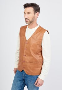 Bruin leren vest met een V-halsontwerp, zes roze knopen en twee voorzakken, gedragen over een wit gestreept overhemd met lange mouwen.