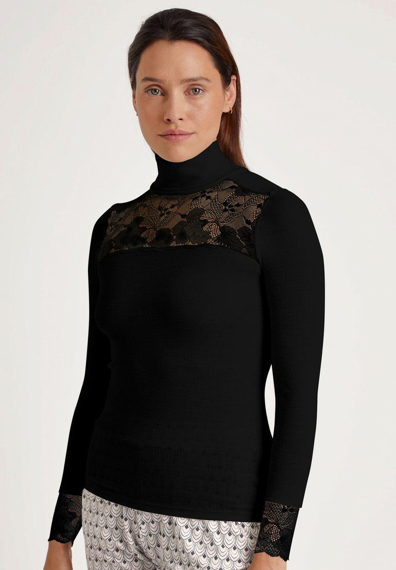 Zwarte langärmelige turtleneck met een doorzichtige zwarte kanten inzet op de borst, textuurstof en kantaccenten op de mouwen.