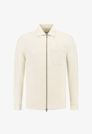 Világos bézs színű, zipzáros dzseki, félgalléros nyakkal, egyetlen mellzsebbel, texturált anyagból, hosszú ujjakkal.