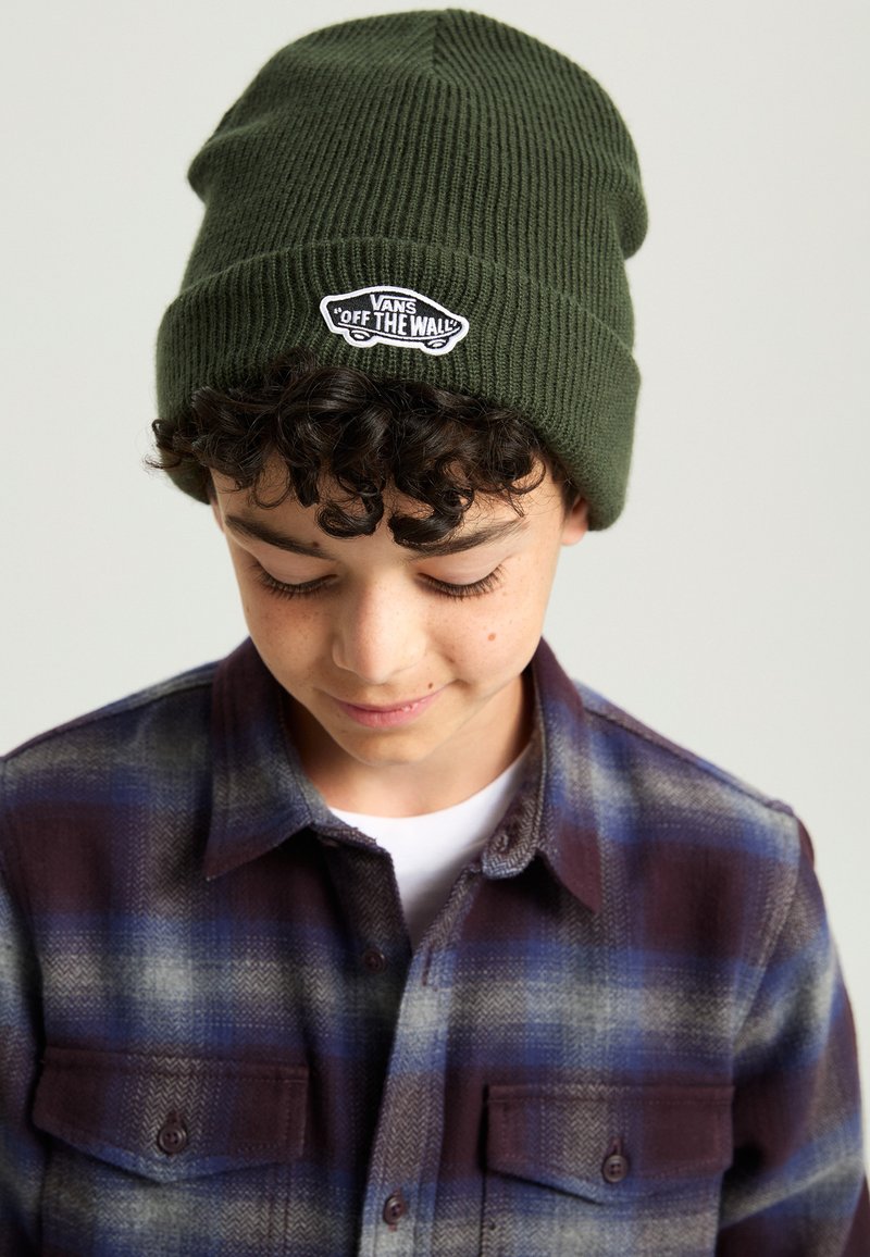 Dark green ribbed knit beanie with a white "Vans Off The Wall" logo patch, worn with a checkered purple and blue flannel shirt.