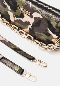 Clutch met camouflagemotief en een gestructureerde afwerking, gouden hardware en een afneembare kettingschouderband. Voorzien van een ritsluiting en logo-accent.