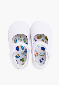 Weiße Leinenschuhe mit runder Spitze, ausgestattet mit einem Riemen und bunten, gemusterten Einlegesohlen, die Fahrzeuge und Tiere abbilden. Flache Sohle.