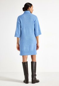 Abito maglione oversize azzurro chiaro con collo alto, polsini e orlo a coste, realizzato in morbido tessuto lavorato a maglia strutturato.