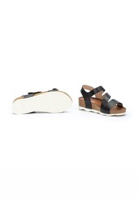 Sandalias de cuero negras con plantilla de corcho, que cuentan con múltiples correas y una suela de goma blanca. Diseño de punta abierta con un tacón bajo en cuña.