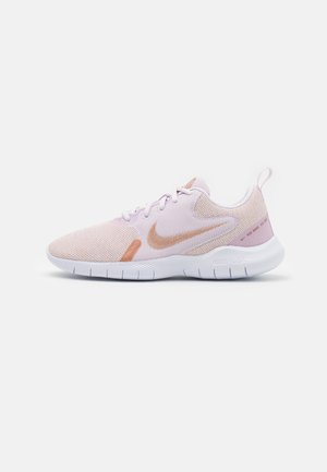 Jasnoróżowy but do biegania Nike z logo Swoosh w kolorze różowego złota, białą elastyczną podeszwą i cholewką z siateczki, widok z boku.