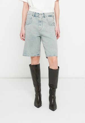 Shorts di denim chiaro con vita alta, cinque tasche e orlo grezzo. Abbinati a stivali marroni in pelle al ginocchio con punte appuntite.