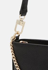 Musta tekstuuriga käekott, millel on kuldne kett ja tarvikud. Omab sujuvat disaini ja eemaldatavat õlarihma.