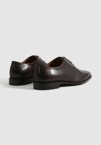 Dunkelbraune Lederschuhe mit glatter Textur, runder Zehenform, Schnürdesign und einem niedrigen schwarzen Absatz. Der Fersenbereich ist leicht abgerundet.