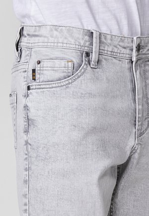 Hellgraue Denim-Jeans im klassischen Fünf-Taschen-Design, mit strukturiertem Stoff und dezenten Verwaschungen. Enthält Metallbeschläge zum Verschluss.
