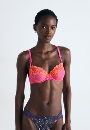 Pink lace bra with orange floral embroidery, underwire support, and adjustable straps; paired with a navy thong featuring colorful floral patterns.