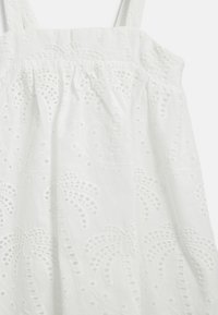 Vitt bomullsklänning med broderade blommönster och ögondetaljer, tunna axelremmar och en rynkad byst.