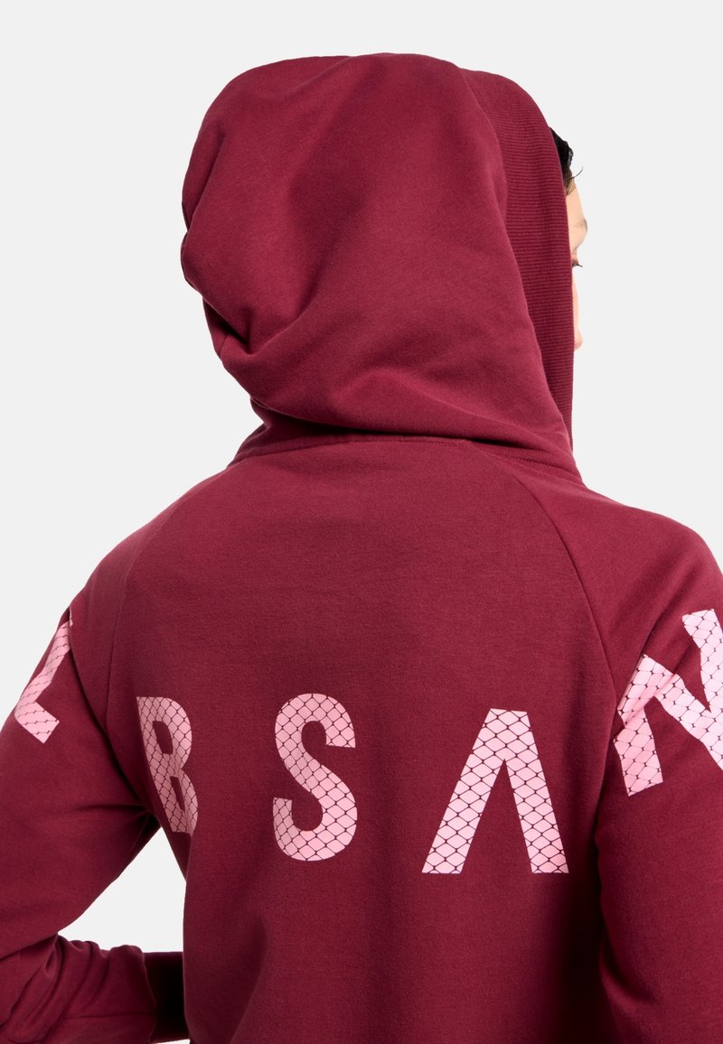 Dunkelroter Hoodie mit großer Kapuze; auf der Rückseite und den Ärmeln mit rosa, netzstrukturierten Buchstaben; glattes, weiches Gewebe mit gerippten Akzenten.