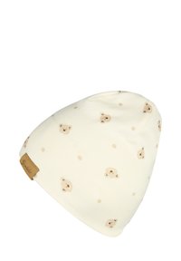 Cream-colored beanie made of soft fabric, featuring a pattern of small bear faces and beige dots. Has a brown leather tag with brand name.
