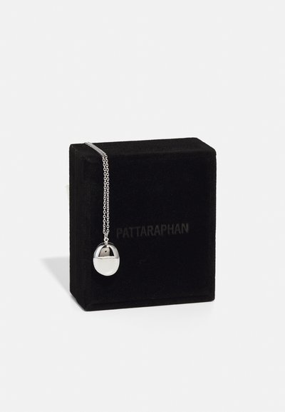 Necklace din argint cu un pandantiv oval având o suprafață lustruită și un accent negru, expus pe o cutie din catifea neagră.