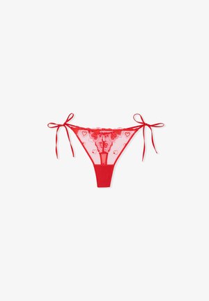 Roter Spitzen-String mit Knotenbändern, vorne transparent mit Herzmustern verziert und hinten in kräftigem Rot.