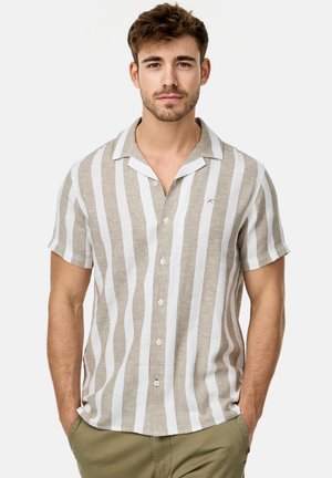 Camisa de manga corta de botones en rayas verticales en tonos marrón claro y blanco, hecha de lino. Presenta un collar estilo camp y un pequeño logo en el pecho.