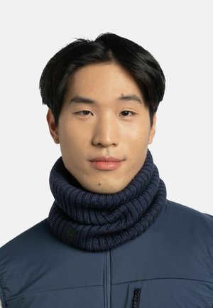 Knit navy blue neck warmer with thick ribbed texture, worn over a dark blue vest. Features a subtle logo patch.