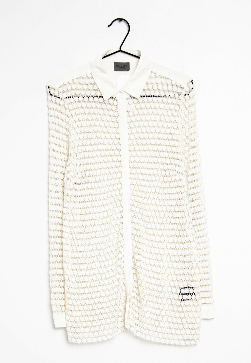 Lange witte blouse met een mesh-overlay, voorzien van een kraag, knoopsluiting en zwarte accenten. De textuur is lichtgewicht en geperforeerd.