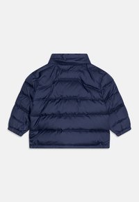 Námořnická péřová bunda s krátkým střihem, vysokým límcem a horizontálními prošívanými sekcemi. Hladká, lesklá látka s elastickými manžetami.