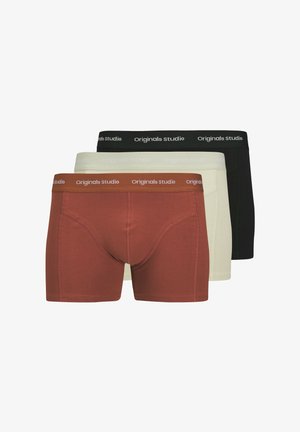 Trois paires de boxers : une couleur rouille, une crème, une noire. Chacune possède une ceinture douce avec l'inscription "Originals studio" en relief blanc.
