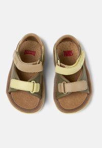 Kaksiväriset sandaalit, joissa on ruskeaa, vihreää ja keltaista materiaalia. Säätömaat kanssa ja teksturoitu sisäpohja. Kevyt malli ja avoimet varpaat.