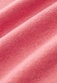 Tessuto lavorato a maglia di color rosa chiaro con una texture liscia, caratterizzato da un sottile rigagnolo e fili fini, creando una superficie morbida e uniforme.