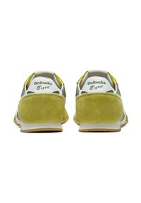 Sneaker giallo e grigio realizzati in suede e rete, con un logo bianco, accenti in contrasto, suola testurizzata e tacchi imbottiti.