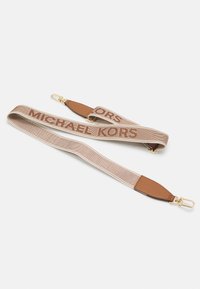 Tkaninový popruh v svetlej béžovej farbe so silným hnedým nápisom "MICHAEL KORS". Detaily zahŕňajú hnedé kožené konce a zlaté kovanie.
