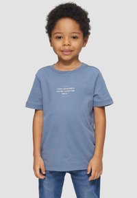 Lichtblauwe katoenen t-shirt met korte mouwen, voorzien van een witte bedrukte tekstontwerp in het midden. Dragen met spijkerbroek.