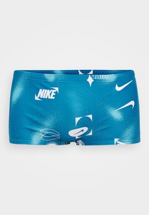Kék úszósort sima texúrával, fehér Nike logókkal és különböző formákban megjelenő absztrakt grafikai mintákkal.