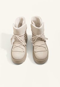 Beige Wildleder-Stiefeletten mit weicher Innenausstattung, ausgestattet mit Schnürdesign und gepolstertem Schaft. Dicke Gummisohle und runde Zehenform.