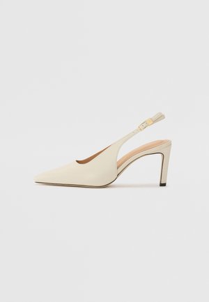 Beige leather slingback heels with a pointed toe, open side design, and a slim high heel. Features a gold accent on the strap.