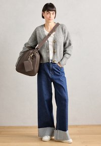 Gray knitted cardigan with gold buttons, white shirt, wide-leg denim jeans with contrasting hem, and a brown shoulder bag with a tag.
