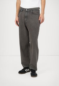 Grijze denimbroek met een ontspannen pasvorm, voorzien van vijf zakken, contrasterende stiksels en een knoopsluiting bij de taille.