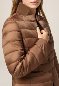 Braun gesteppte Jacke mit einem Cordkragen, Knopfdetails und Seitentaschen. Sie zeichnet sich durch ein weiches, glänzendes Material und eine taillierte Silhouette aus.