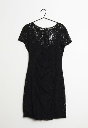 Robe noire à manches courtes en dentelle avec motif floral suspendue à un cintre noir sur fond blanc.