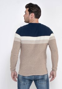 Pullover lavorato a maglia in blu navy, crema e khaki. Presenta righe orizzontali, scollatura rotonda e tessuto texture. Maniche lunghe con polsini aderenti.