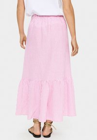 Gonna maxi a strisce rosa e bianche con vita elastica e orlo arricciato. Il tessuto è leggero, offrendo una silhouette fluida.