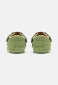 Grüne Wildlederschuhe mit abgerundetem Rücken, die ein einfaches Design und Klettverschlüsse aufweisen, mit einer strukturierten Oberfläche und einem leichten Absatz.