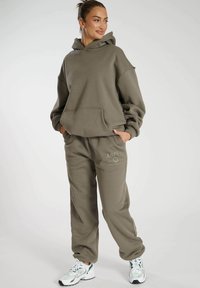 Khaki sweatshirt och joggers set i mjukt material. Huvan har en framficka; joggers har ett broderat "ASPEN COLORADO"-motiv.